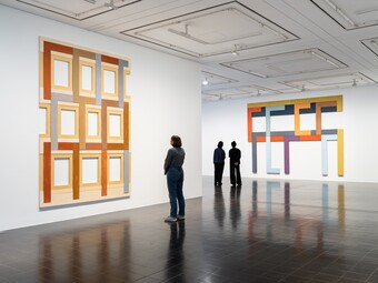 Drei Personen betrachten Kunstwerke in einer Galerie