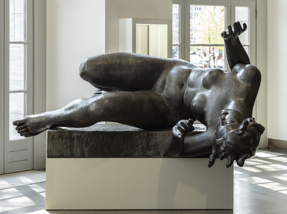 Große Bronzeskulptur von Aristide Maillol einer liegenden Frau auf weißem Sockel in hellem Museumsraum