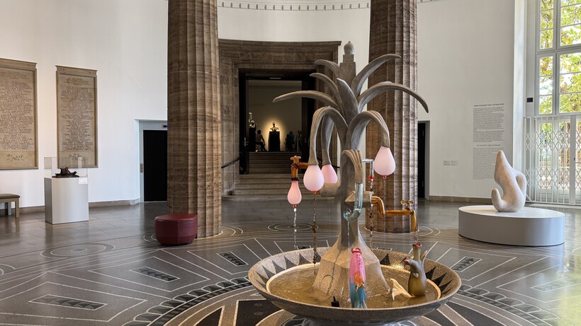Ausstellungsraum mit Säulen, Terrazzoboden und Brunnen im Vordergrund